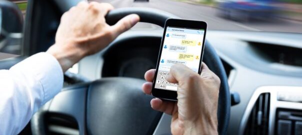 Autofahrer hält ein Handy in der Hand