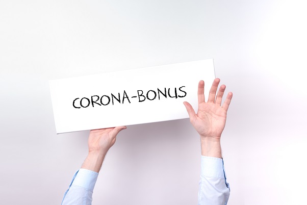 Mann hält Schild mit Aufschrift Corona-Bonus