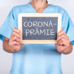 Medizinischer Mitarbeiter mit Corona Prämien Schild