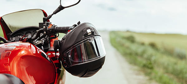 Schwarzer Motorradhelm hängt am Lenkrad eines roten Motorrads