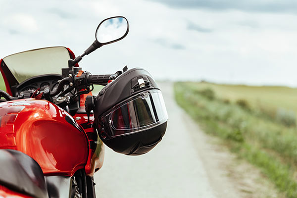 Schwarzer Motorradhelm hängt am Lenkrad eines roten Motorrads